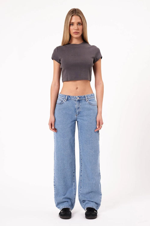 Woman wearing a gray crop top and blue jeans on a white background