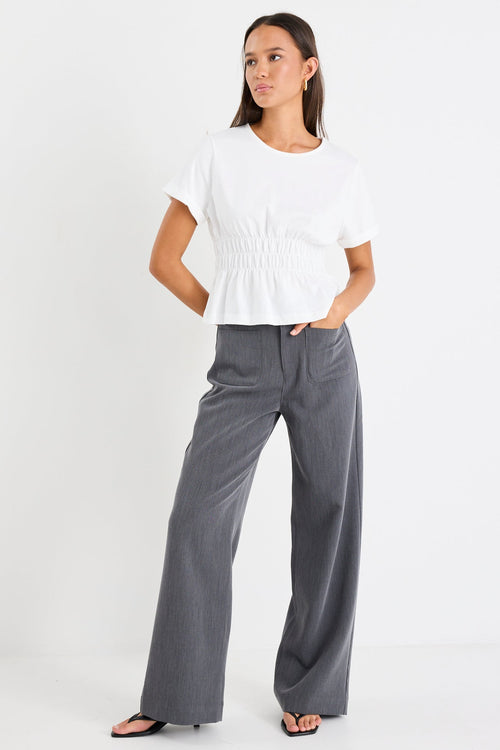 Woman wearing a white top and gray pants on a white background
