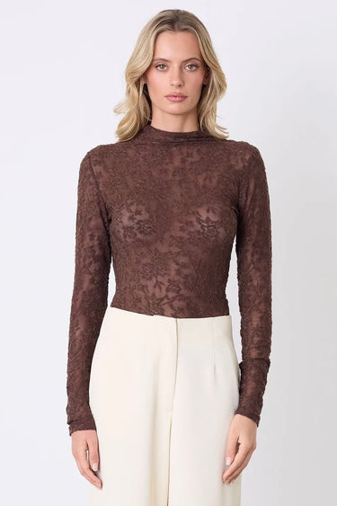 Model wears a lace brown long sleeve top with a high neck