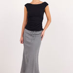 A woman modeling a black short-sleeve top and a long, flared gray skirt against a plain white studio background.