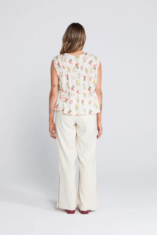 woman wearing a cream floral top and cream pants