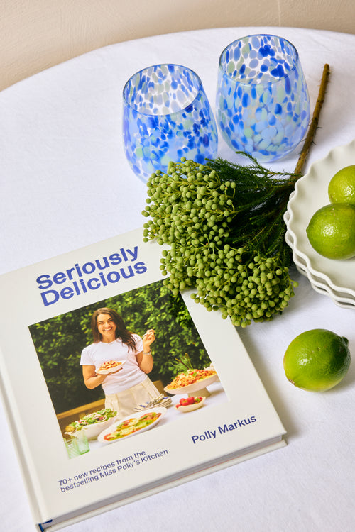 Cookbook titled 'Seriously Delicious' by Polly Markus with decorative items on a table.