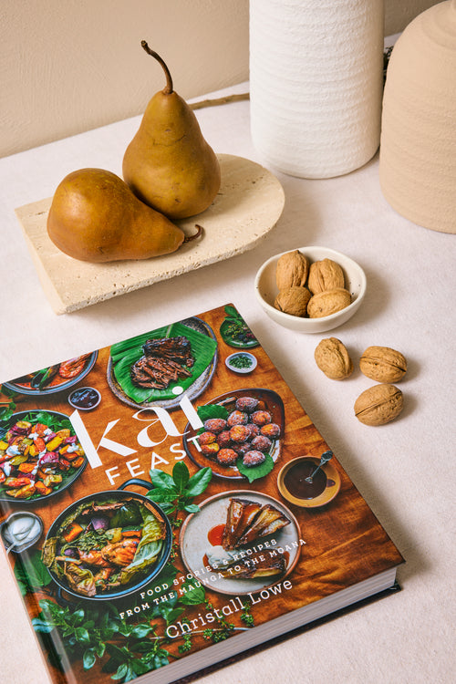 Cookbook titled 'Kah Feast' with pears and walnuts on a table