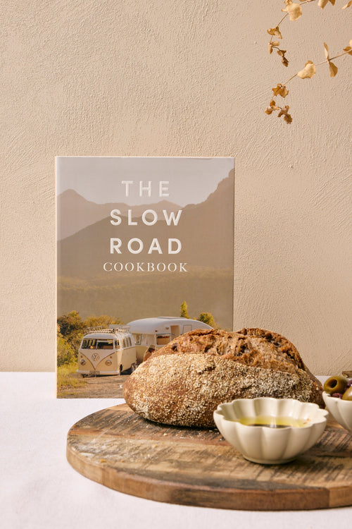 The Slow Road Cookbook on a table with bread and olives