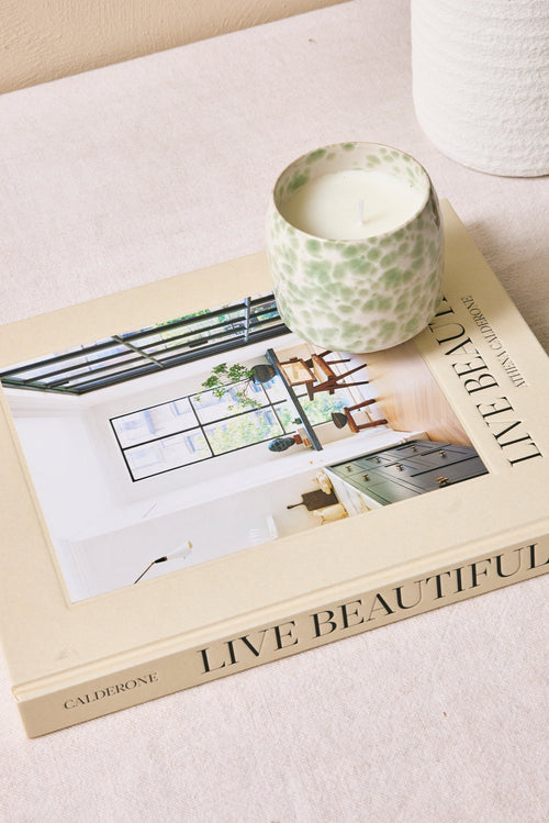 Book titled 'Live Beautiful' with a candle and diffuser on a light surface