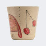 Beige ceramic cup with red cherry design on a white background