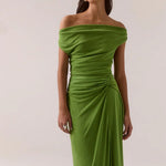 Woman wearing a green off-shoulder gown against a white background