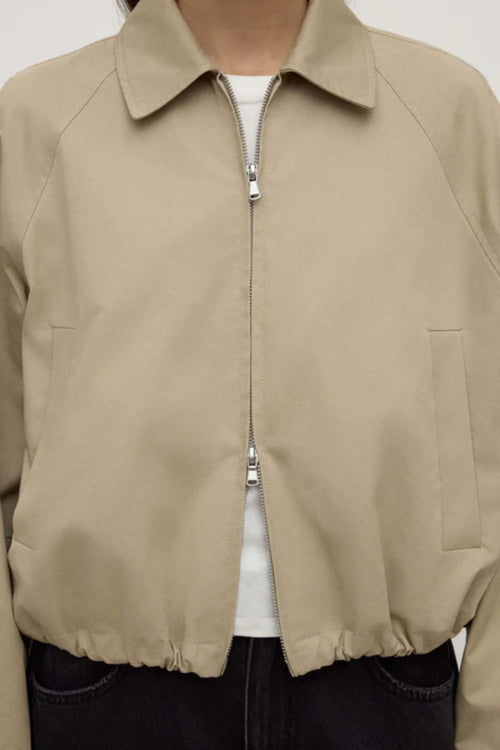 Beige jacket worn by a person on a white background