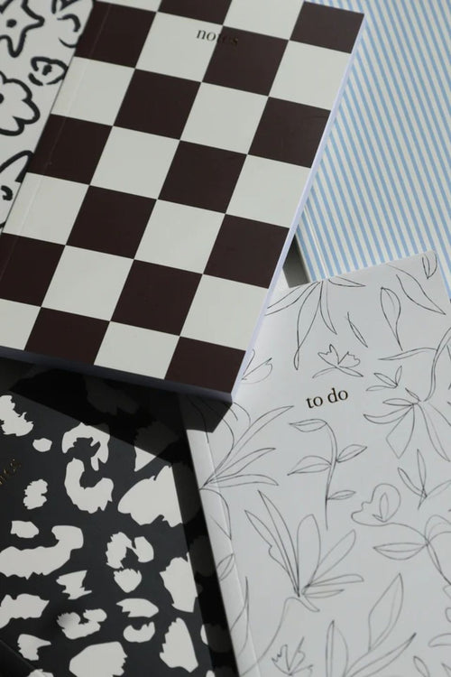 Collection of notebooks with various patterns including checkered, leopard print, and floral.