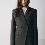 Woman wearing a dark green suit against a white background