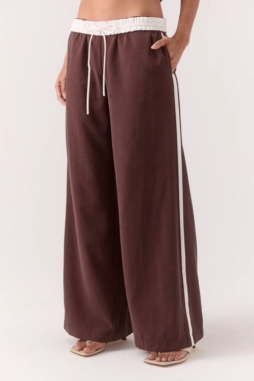 Brown wide-leg pants with a white stripe on a white background