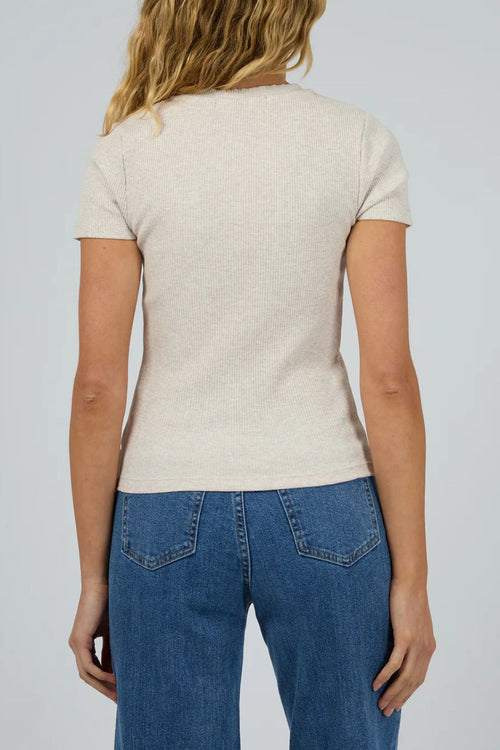 Person wearing a beige t-shirt and blue jeans on a plain background