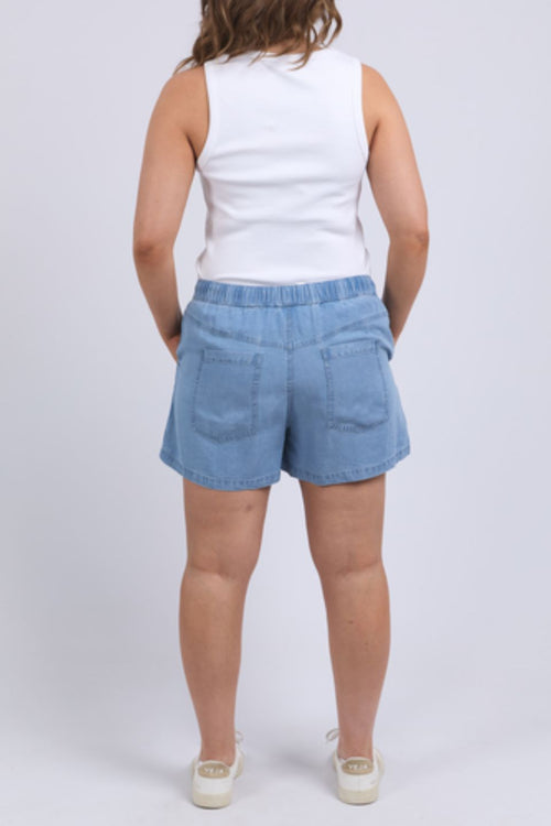 Woman wearing chambray denim shorts and white tank