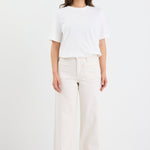 Woman wearing a white top and light-colored pants on a white background