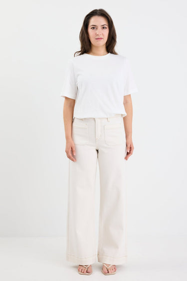 Woman wearing a white top and light-colored pants on a white background