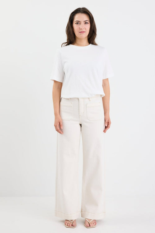 Woman wearing a white top and light-colored pants on a white background