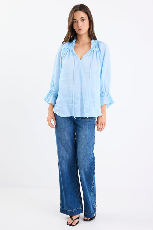 Woman wearing a light blue blouse and blue jeans on a white background