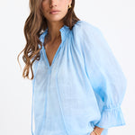 Woman wearing a light blue blouse with a white background