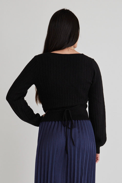 Model wears a black wrap knit