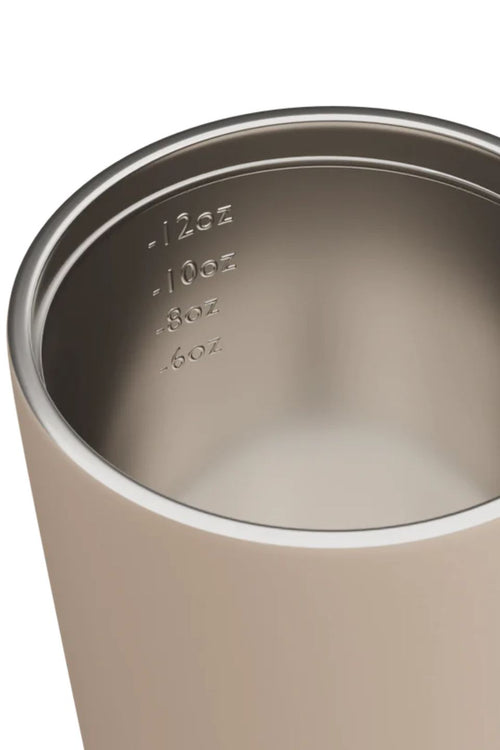 Close-up of a metallic tumbler with measurement markings on a white background