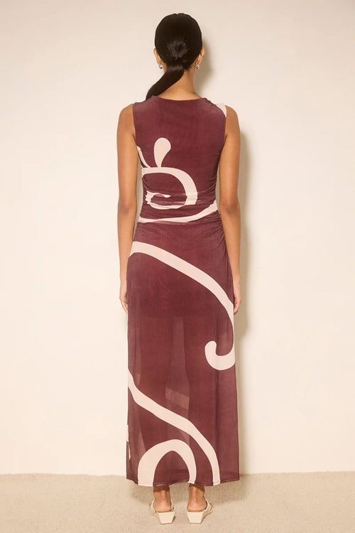 Woman wearing a burgundy dress with white abstract patterns on a beige background