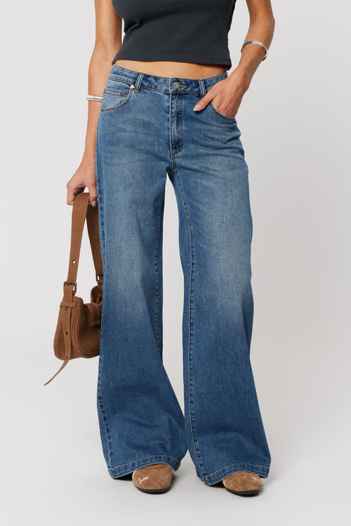 Person wearing blue flared jeans on a white background