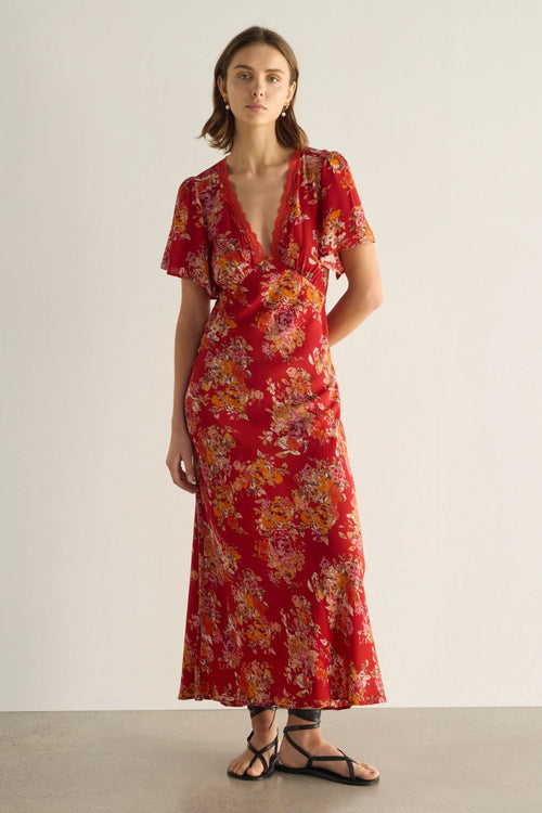 Woman wearing a red floral dress against a plain background