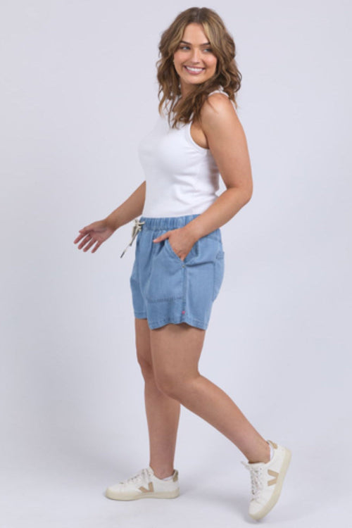 Woman wearing chambray denim shorts and white tank