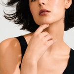 Woman with short dark hair wearing a black top against a light background