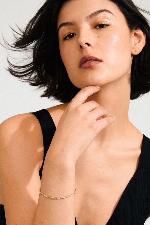 Woman with short dark hair wearing a black top against a light background