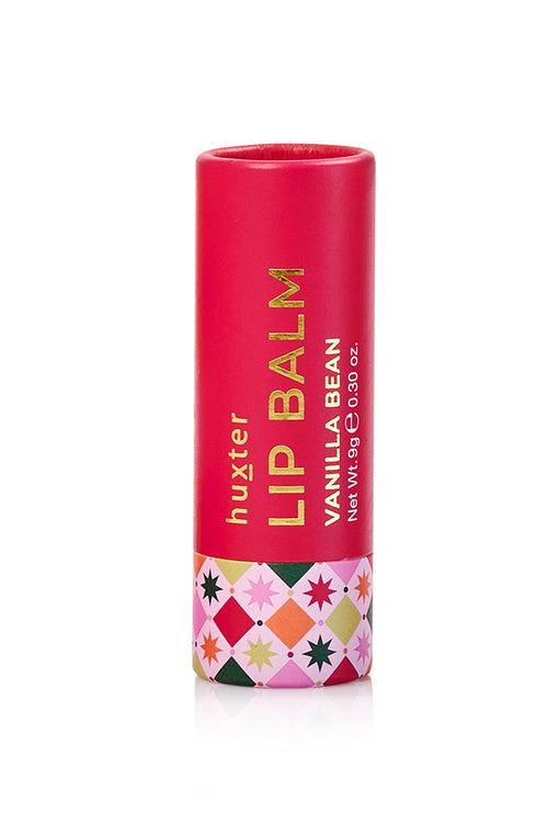 A single tube of Huxter Lip Balm in Vanilla Bean, featuring a bright pink-red body with gold lettering and a colorful geometric pattern band at the bottom, set against a plain white background.
