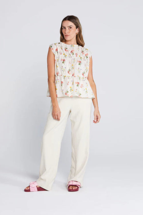 woman wearing a cream floral top and cream pants