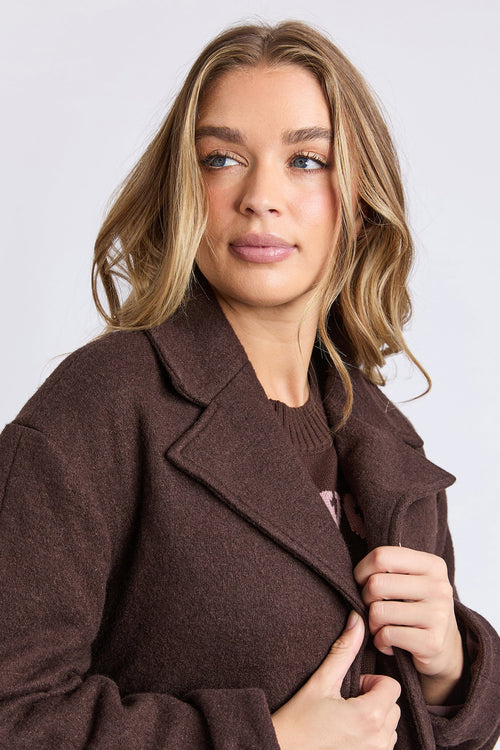 Woman wearing a brown coat against a plain background