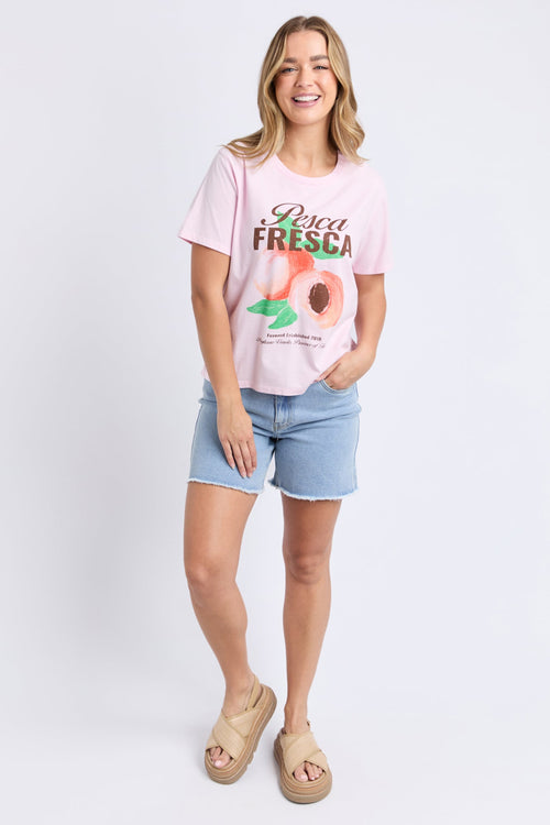 Woman wears a pink printed top and blue shorts