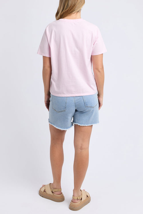 Woman wears a pink printed top and blue shorts