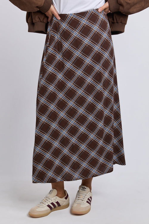 Person wearing a brown plaid skirt with a plain background