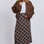 Woman wearing a brown jacket and plaid skirt on a white background