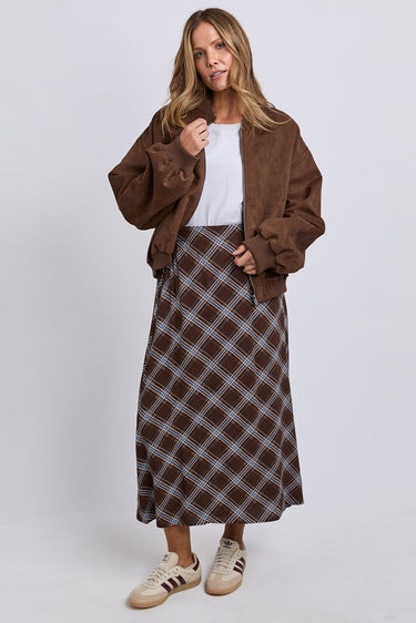 Woman wearing a brown jacket and plaid skirt on a white background