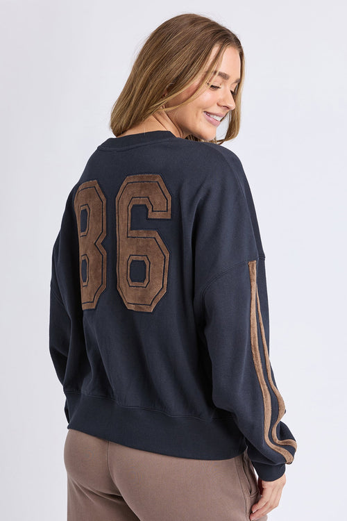 Woman wearing a navy sweatshirt with '86' on the back against a white background