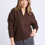 Woman wearing a brown sweater and gray pants on a white background