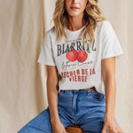 Woman wears a white apple print shirt and blue denim