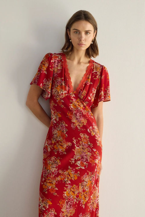 Woman wearing a red floral dress against a plain background