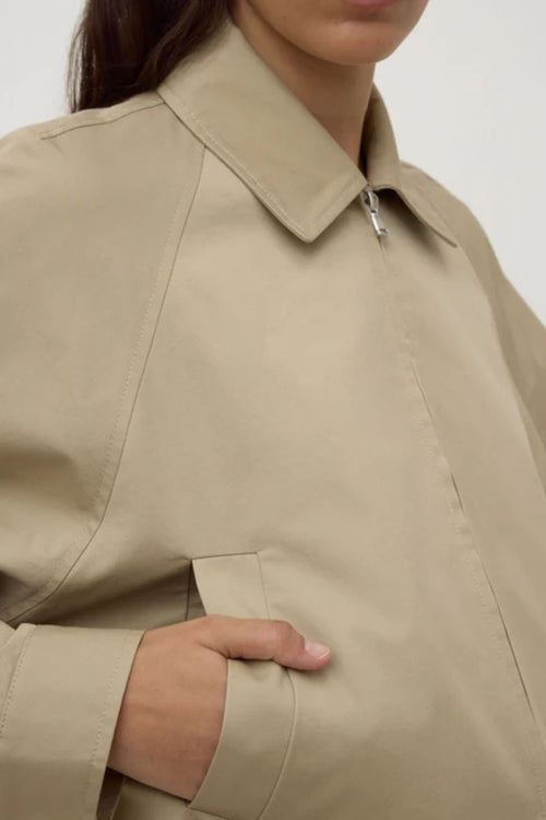 Close-up of a beige trench coat with a neutral background