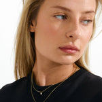Woman wearing a black top and gold necklaces on a white background