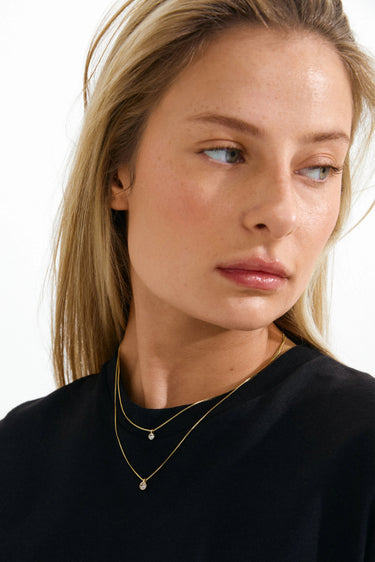 Woman wearing a black top and gold necklaces on a white background