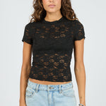 Woman wearing a black lace top and light blue jeans on a white background