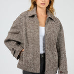 Woman wearing a brown patterned jacket on a light gray background