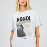 Woman wearing a white t-shirt with 'Bondi' graphic design on a plain background