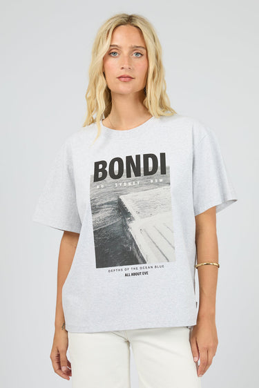 Woman wearing a white t-shirt with 'Bondi' graphic design on a plain background