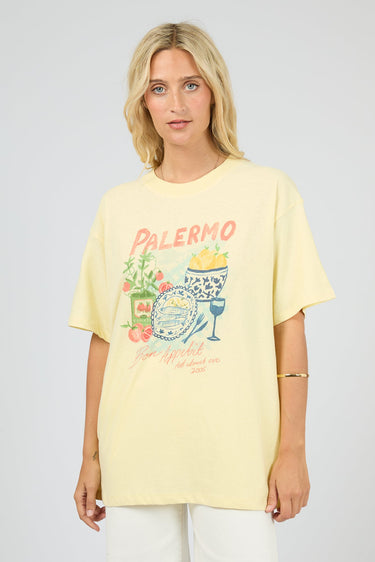 Woman wearing a yellow t-shirt with a graphic design on a plain background